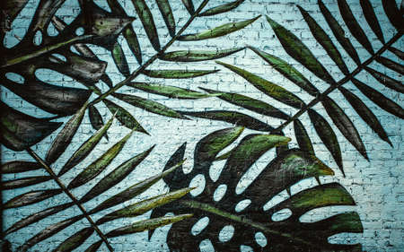 Tropical leaves are painted on a brick wall. Drawing on a white brick wal. Beautiful floral background.の写真素材