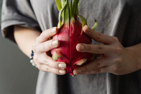 Close-up of female hands holding a vibrant pitahaya fruit.