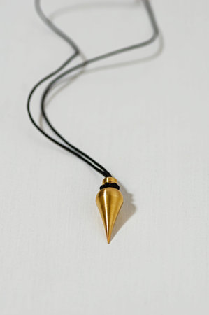 Brass pendulum with cord for dowsing and energy healing. Used in bioenergetics to detect energy...