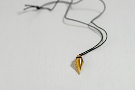 Brass pendulum on black cord designed for energy diagnostics, and holistic healing. Used in spiritual practices to detect energy blocks, enhance intuition, and balance biofields.の写真素材