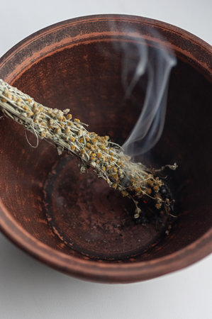 Closeup of a freshly made mugwort smudge stick in a clay bowl, demonstrating natural herbal texture. Ritual tool used for energetic cleansing, purification, and creating a balanced, healthy space.の写真素材