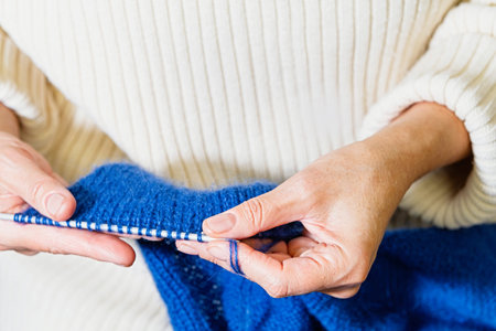 Woman hands holding blue mohair knitting project on needles, working with soft fluffy yarn, handmade...
