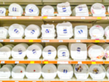 Blurred background. Shelves with goods. Household products. goods for the kitchen. Sale of plates. Score. Hypermarket Dishes White dishes on the shelves.の写真素材