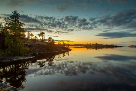 Dawn over the lake. The clouds are reflected in the water. Islands in the rays of dawn. Wild nature. Karelia. Russia. Nature of Russia.の写真素材