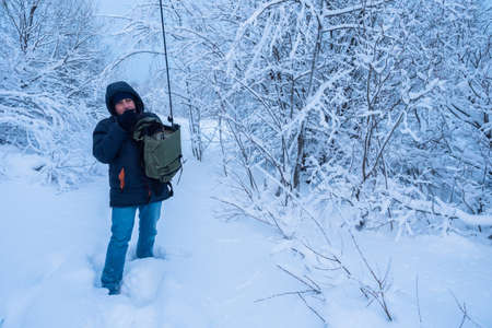 A man carries a walkie-talkie. Radio station with short waves. Hobby. VHF radio station. Professional KV transceiver. Winter. A man receives a signal on the radio station.の写真素材