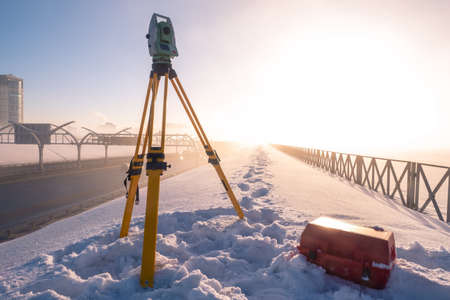 Theodolite. Topographic equipment. Theodolite stands on a tripod. Topographical measurements. Measurement of soil creep. Construction works. Construction measurements. The work of the tapographer.の写真素材