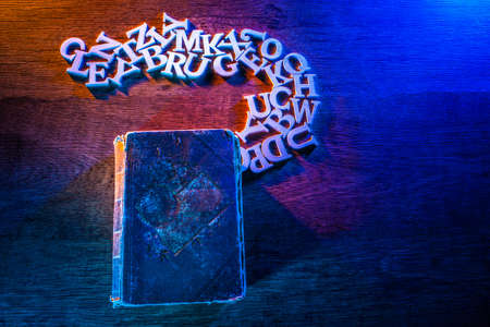 on the table is an old book. Reading books. Letters fly out of the open book.の写真素材
