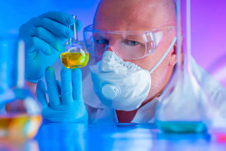 Chemical examination of fuel and lubricants. Chemist conducts a test. Researcher studies the results of the experiment. Chemical laboratory. Chemist in a protective mask. Respiratory Protectionの写真素材