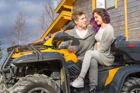 Cottage in the woods. ATV. Camping. A man and a woman are discussing the journey. The girl and the guy are sitting on the ATV. Leisure. Sports entertainment.の写真素材