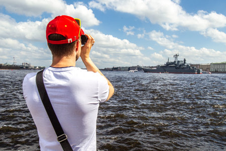 A man looks through binoculars. Warship A man looks through binoculars at a warship.