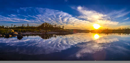Sunset in the reflection of water. The nature of Finland. Camping. Unusual clouds. Reflection of clouds in the water.の写真素材