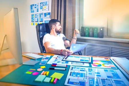 Male graphic designer at the desk. Design for mobile devices. Close-up pictures of the application designers are planning the prototype of the website and applications for mobile phoneの写真素材