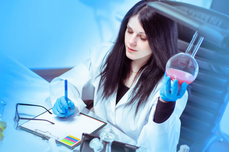 Woman Chemist doing scientific work. Glass flask in the hands of a scientist. Researcher woman....