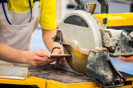 Worker cuts tile. Circular Saw. Finishing work. A man uses a circular saw. Construction site. Circular saw with water supply.の写真素材