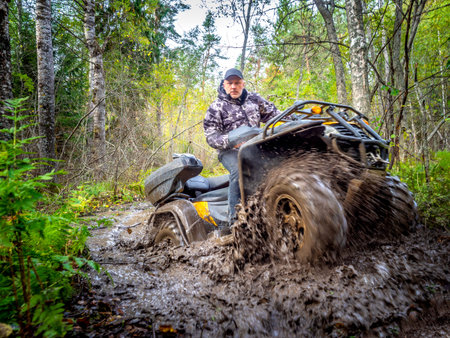 A man rides on ATV through the mud. Riding a quad bike. A man rides an all-terrain vehicle. Riding...