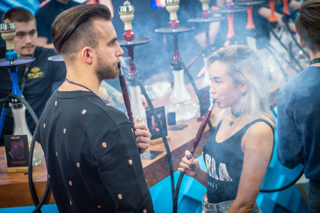 A man tastes the scent of hookah tobacco. Smoke. Smoking accessories. Tabaka. Hookah Club Show. Exhibition of hookahs. 9.3.2019. Russia. Saint Petersburgのeditorial素材