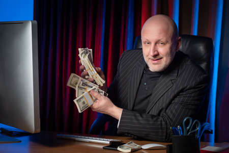 Businessman rejoices income. The man is happy with the earnings. Businessman in a suit. Successful business. Cheerful look. Money in hand.の写真素材