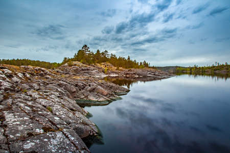 Finland. Lake. Morning on the lake. Reflection of the sky in the water. Pines on the rocks. Nature of the north.の写真素材