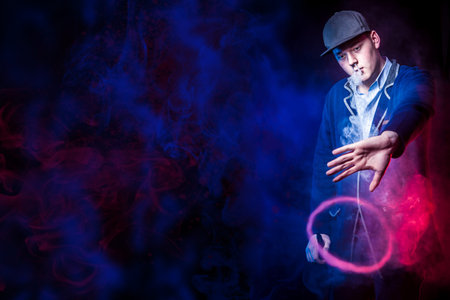 A man with vape. Young guy smokes showing smoke tricks. Vaper. Smoking electronic cigarettes....