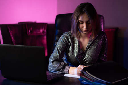 Work at the computer. A woman takes notes on work. Performing work at the computer. Remote work.の写真素材