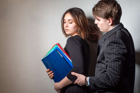 Sexual harassment at work. A man pesters his colleague. Sexual aggression to the woman. Harassment. The girl with the head.の写真素材