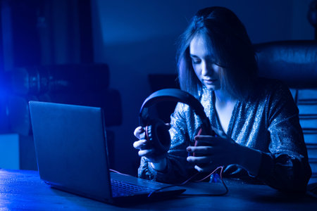 The girl puts on headphones. Remote work. A woman works through the Internet. The girl listens to...