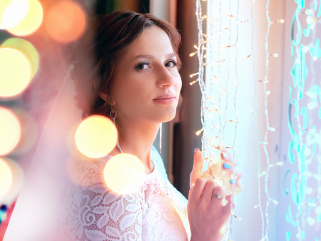 Bride with a gentle smile. Wedding. The bride touches the garland. The girl is looking at the...