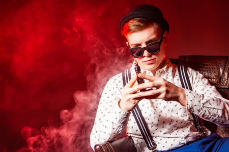 The man smokes. A man is considering an electronic cigarette. Steam from vape. A man with vape....