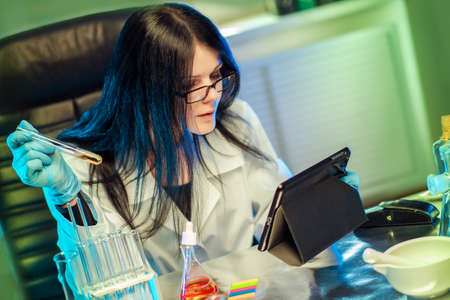 Chemical laboratory. Chemist looking scientific seminar on the tablet. Chemical expertise. Drug tests. Clinical trial. Medicine. Pharmacology.の写真素材