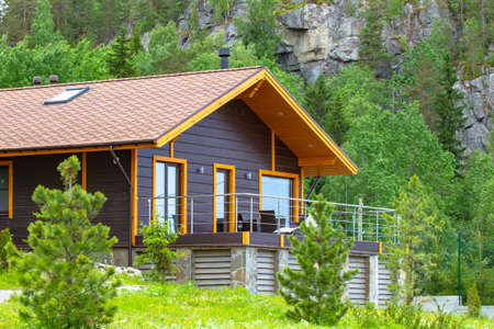 Country house on the background of the mountain. Single-storey cottage in the country. Rental cottages for recreation. Purchase and sale of suburban real estate. Rest in the house in nature.の写真素材