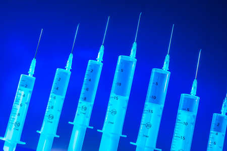 Syringes on a blue background. The vaccine is in the syringe. Medical services.の写真素材