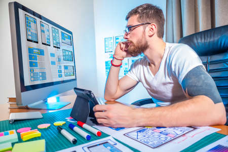Ux ui design. Designer sinhroniziruete computer and tablet. The process of prototyping in software development. Development of mobile applications. Wireframing.の写真素材