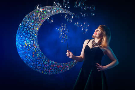 Girl on a background of soap bubbles. Show with soap bubbles. Many soap bubbles. Girl animator children's holiday. The girl is blowing bubbles.の写真素材