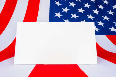 A sheet of paper on the background of the American flag. Mockup with the American flag. Flag of the United States of America and white space for text. Patriotic American frame.の写真素材