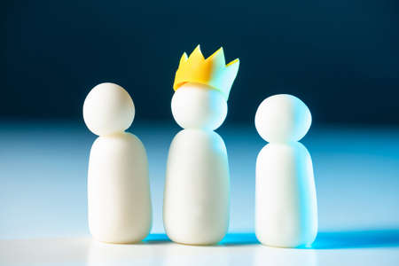One of the three little men wears a crown. Leadership in the team. The chief directs his subordinates. The official hierarchy. Distribution of roles in the company. Business structure.の写真素材