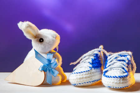 Pregnancy concept. Newborn booties. Soft toy bunny with a symbol of the heart. The baby layette. Gifts to the newborn. Newborn. Baby. Motherhood. Taking care of baby.の写真素材