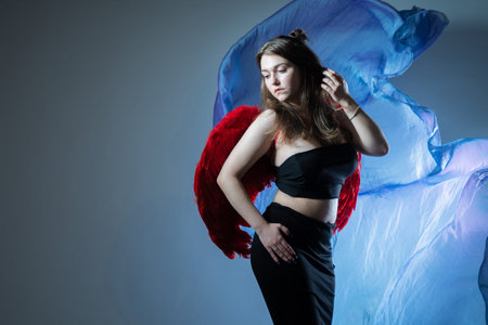 Portrait of a girl with wings. A woman poses against the background of developing matter. Girl on a gray background with a place for text. The girl poses and looks away.の写真素材