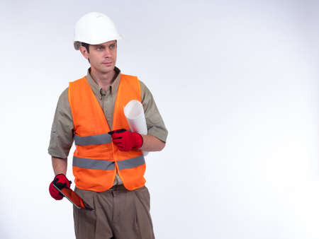 Architect on a white background. A man in a construction helmet with drawings in his hands. A man in construction gloves is holding a tablet. The Builder looks away.の写真素材