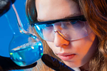 Girl with a flask. The chemist is holding a flask. Chemical research. Woman researcher. Researcher in the laboratory. The girl is studying chemistry.の写真素材