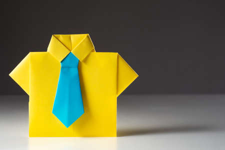 Symbolic image of the employee. Origami in the form of an office worker. Business attire. Business suit made of paper on a gray background with place for text.の写真素材