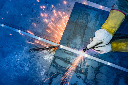 A worker cuts a sheet of metal with a plasma metal cutter. Plasma cutting of metal. Equipment for...