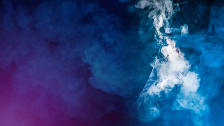 Smoky VAPE background. Vaper in a cloud of smoke. A man in a top hat and glasses smokes VAPE. Space for text. VAPE shop. E-cigarette smoker on a dark background.の写真素材