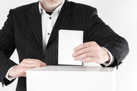 A person with a ballot next to the voting basket. A man in a business suit at a polling station....