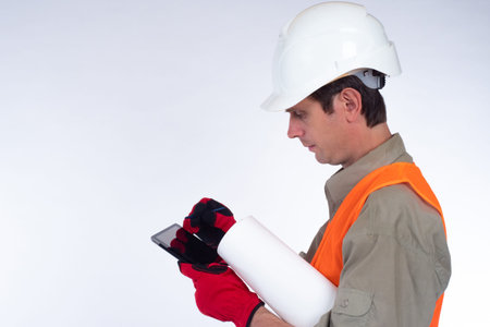 Builder with an electronic tablet and drawings. Construction foreman in a white helmet. The engineer...