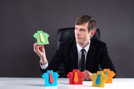 The concept of recruitment. Work with personnel. HR Manager studies origami men. Paper office suits symbolize different people. The boss chooses the right employee.の写真素材