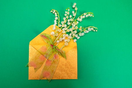Envelope with lilies of the valley on a green background. Bouquet in an envelope. The concept of...