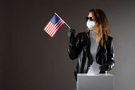 Voting in the USA Presidential election. An American woman votes in an election in a coronavirus pandemy. A woman in rubber gloves and a mask at the election. Security measures at polling stations.の写真素材