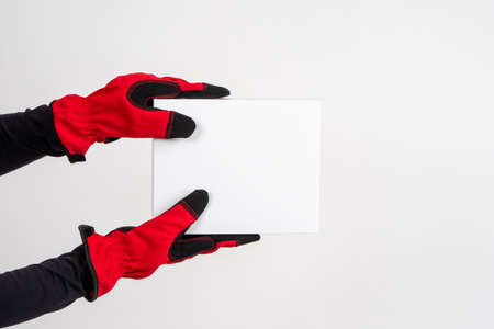 Delivery concept with space for text. Home delivery of goods. Online trading. Red-gloved hands hold a white box. Delivery of online orders.の写真素材