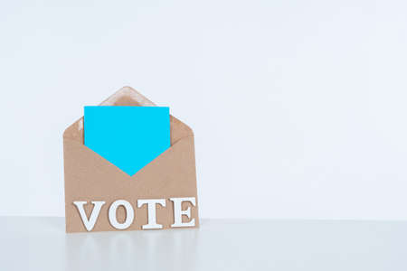 The concept of voting in elections with space for text. Craft envelope with a ballot and the word vote on a white background. Call to vote in elections. The importance of each vote in voting.の写真素材