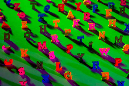 Latin letters on a green background. The concept of getting an education. The letters on the table cast shadows. Lots of English letters in random order. The richness of the language.の写真素材